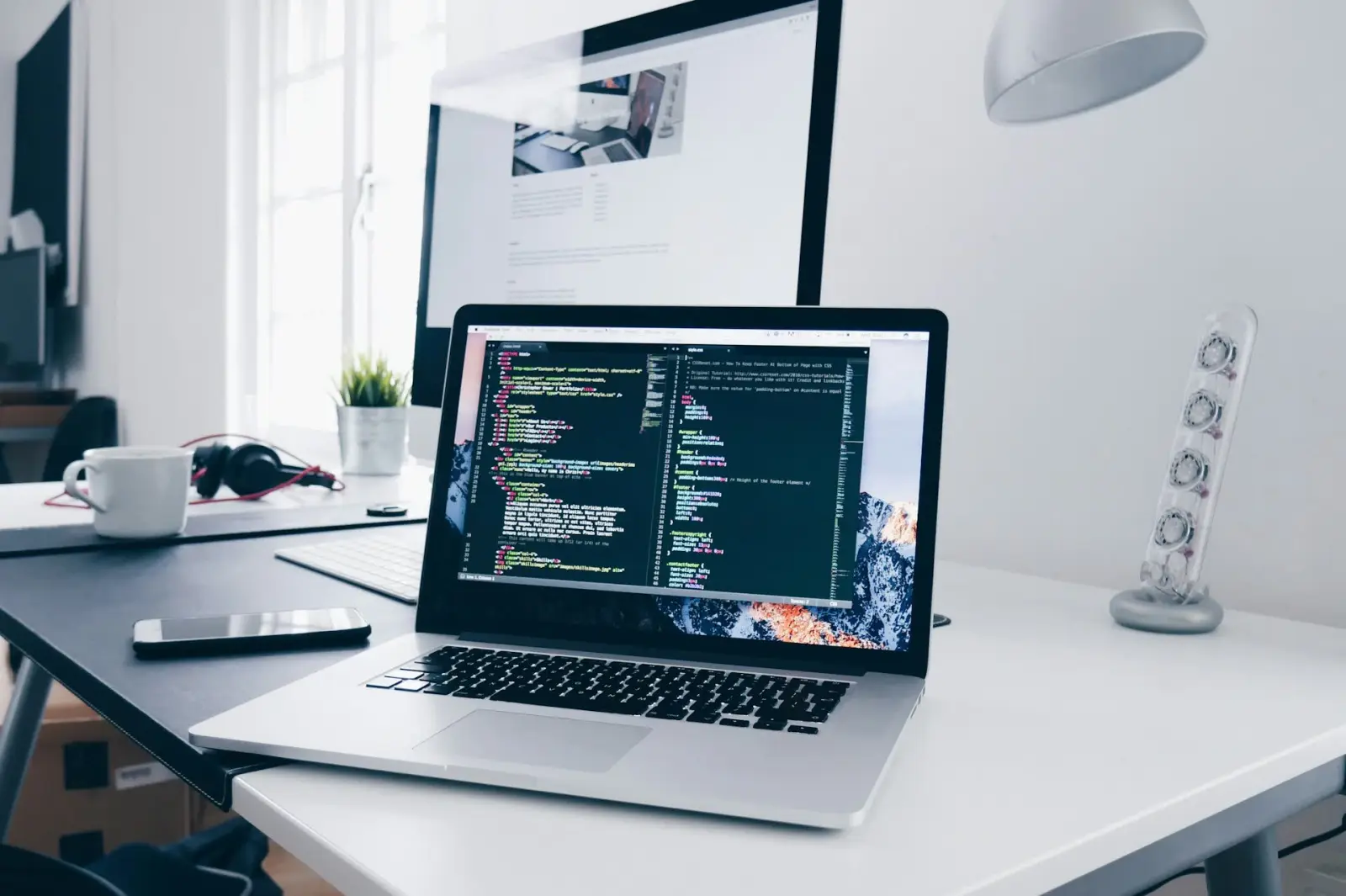 Developer workspace with multiple screens showing code and modern UI - dark cinematic lighting